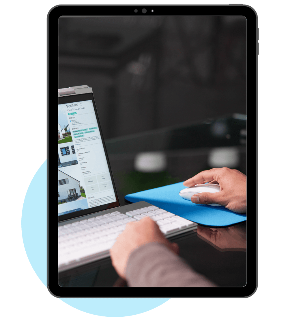 Person browsing real estate listings on a laptop with a keyboard and mouse.