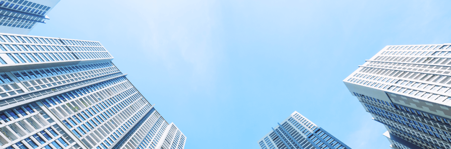 A low-angle view of three identical white tall buildings against a clear blue sky.