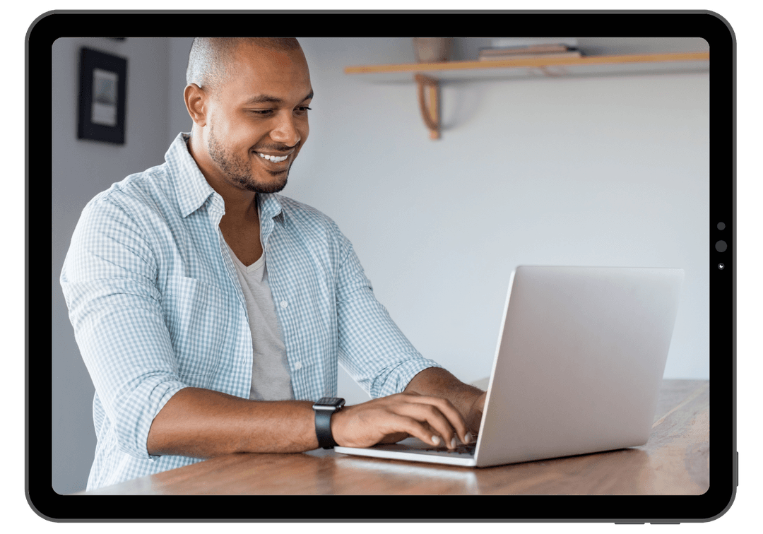 A happy man using his laptop to study courses from Leap Real Estate.
